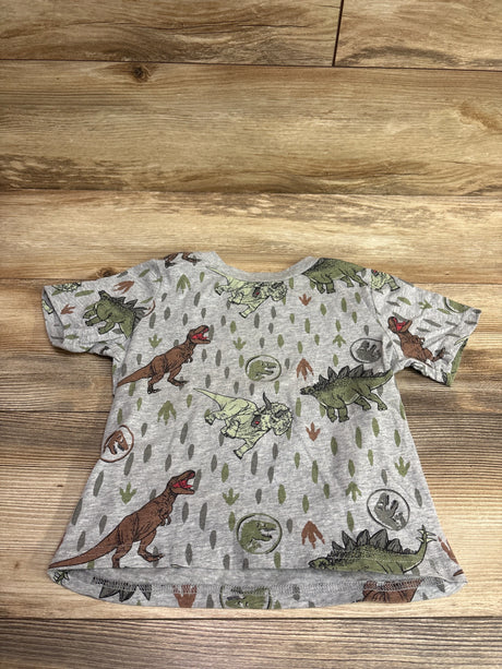 Top view of Jurassic World gray shirt in size 4T showcasing an allover dinosaur print with a wood background