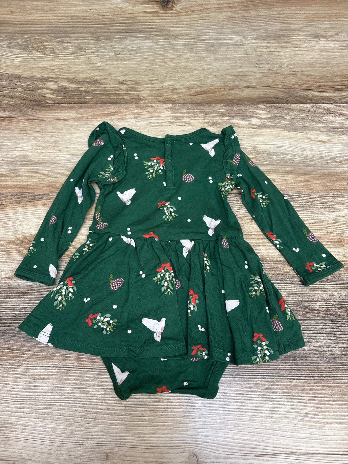 Front view of green Kyte Baby Bamboo Mistletoe Twirl Bodysuit Dress showcasing long sleeves and twirl skirt on wood