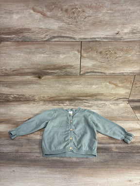Light green baby cardigan with wooden buttons on wooden floor background