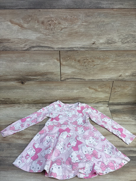 Top view of a pink Sanrio Hello Kitty and Friends long sleeve dress showcasing an allover character print with a flared skirt on a wood background