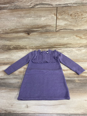 Purple knitted long sleeve baby dress with ruffled lace detail on wooden background