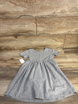 Flat-lay of girl's grey short-sleeve dress showing gathered waist and flared skirt on wood floor