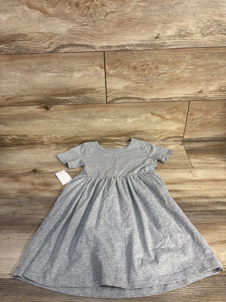 Flat-lay of girl's grey short-sleeve dress showing gathered waist and flared skirt on wood floor