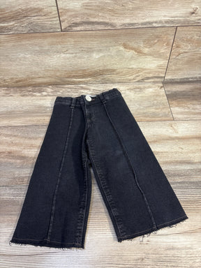 Flat lay of toddler black Zara wide leg jeans with frayed hem and center seams on light wood floor