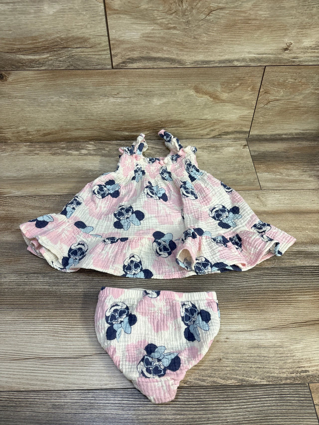 Flat lay of gauze baby dress and matching bloomers with pink and navy Minnie Mouse print on wood floor