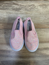 Top-down view of Cat and Jack Yana pink glitter slip-on sneakers showing iridescent glitter and white soles on wood floor