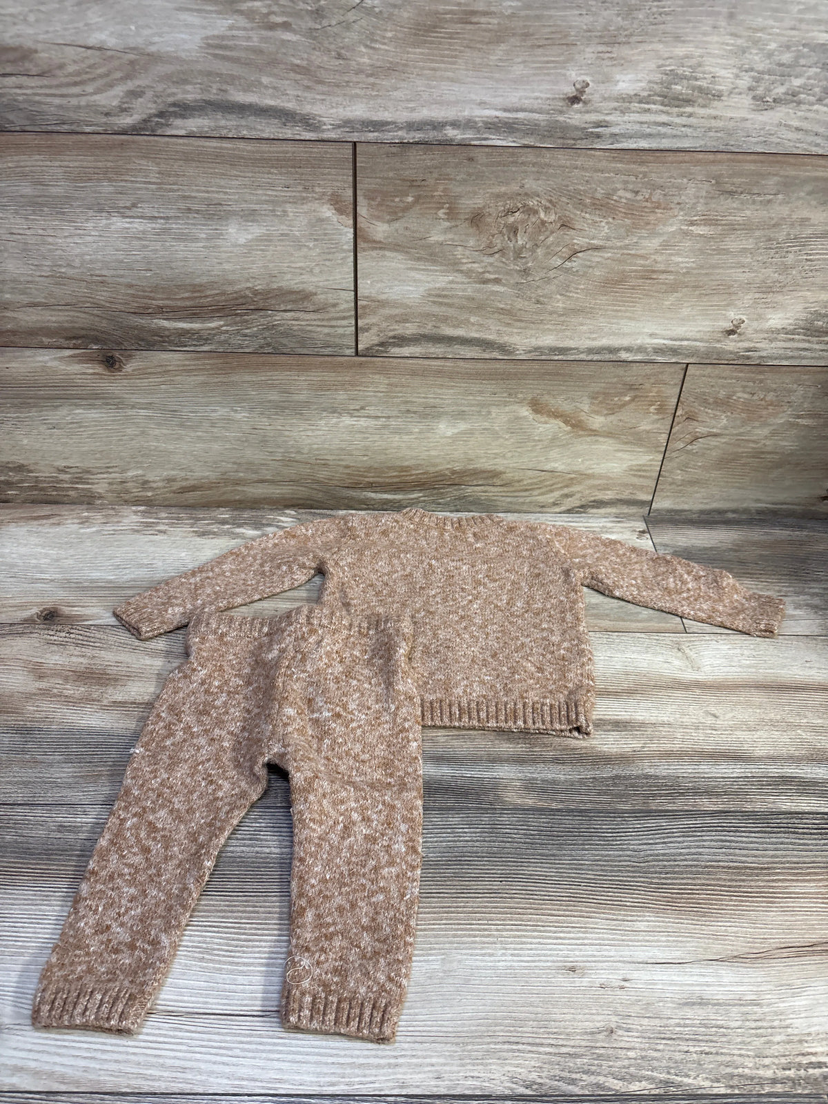 Flat view of Old Navy SoSoft sweater and pants set in brown, size 6 to 12 months, with ribbed cuffs on wood-look flooring