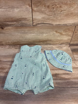 Flat lay of green and white seersucker baby romper and matching bucket hat showcasing embroidered golf motifs on wood background