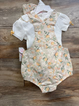 Front view of 2-piece baby shirt and lemon-print shortalls set with white ribbed top and bow accents on wooden background