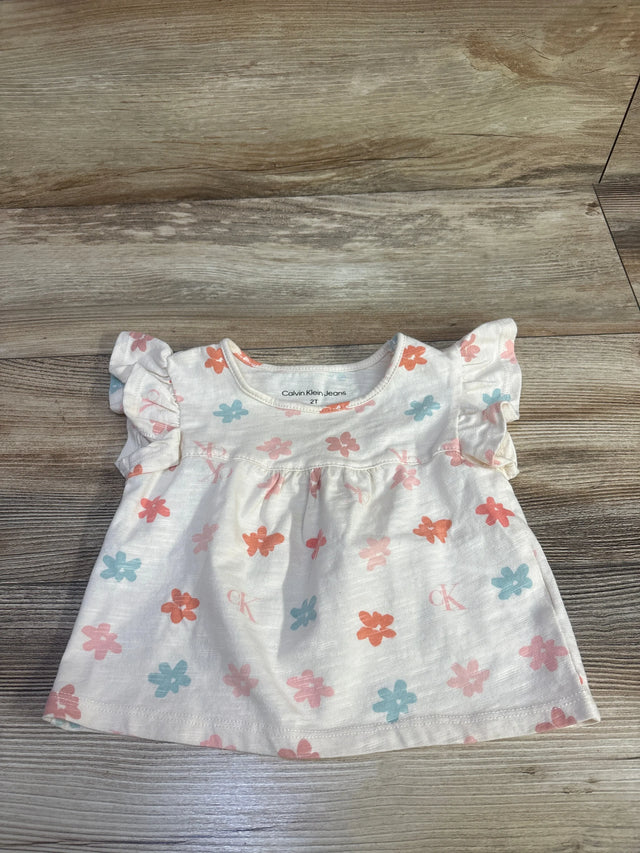 Front view of Calvin Klein toddler flutter-sleeve shirt showing ruffle sleeves and pink and blue floral print on wood background