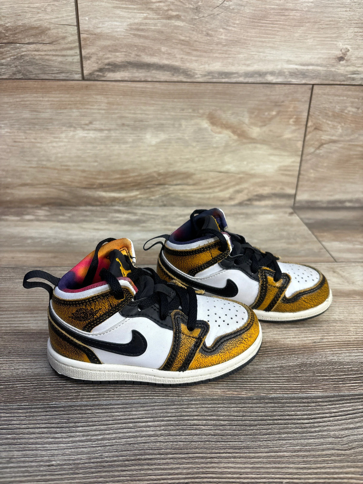 Side view of Air Jordan 1 Wear Away Taxi toddler sneakers size 8C showing black Swoosh and yellow upper on wood floor