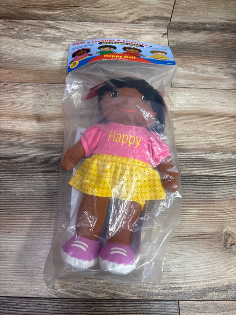 Front view of Feelings and Emotions Washable Happy Doll in packaging, with pink shirt, yellow skirt, and wood floor