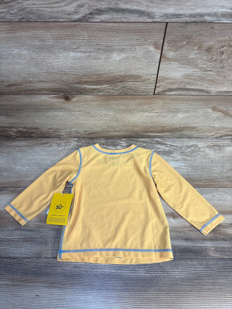 Yellow long-sleeve kids UV protection swim shirt with UPF 50+ tag, blue trim, laid on wood floor