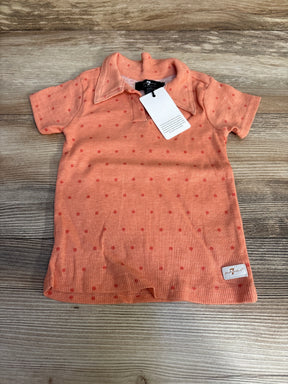 Flat lay of peach 7 For All Mankind polo shirt (24M) with red polka dots, ribbed knit, collar and brand tag on wood