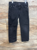 Black denim kids jeans with front pockets and belt loops on wood background