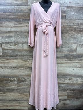Pink maternity wrap dress with long sleeves and tie waist, displayed on mannequin against wood panel wall