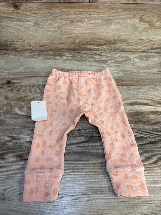 Peach pink baby pants with polka dot pattern and fold-over cuffs on wooden background