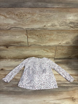 Top view of Oshkosh long sleeve floral shirt in white showcasing an all-over floral pattern on a wood-grain background