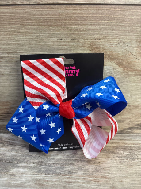 Front view of NEW Fourth Of July Large Hair Bow showcasing red white and blue American flag print grosgrain ribbon on branded card on wood plank floor