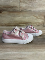 Pair of pink glitter toddler sneakers with bows and white soles on wood floor