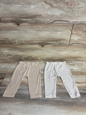 Two pairs of baby leggings, solid beige and gray striped, laid flat on wood floor for kids clothing resale