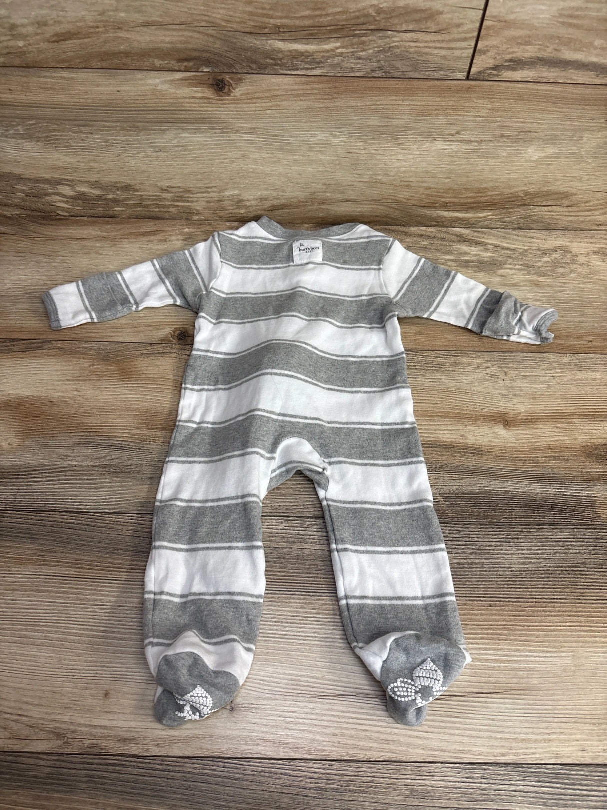 Gray and white striped baby footed sleeper from Burt's Bees on wood surface