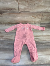 Top-down view of pink footed baby sleeper with front zipper, small floral print and 'LITTLE SISTER' text on wood background