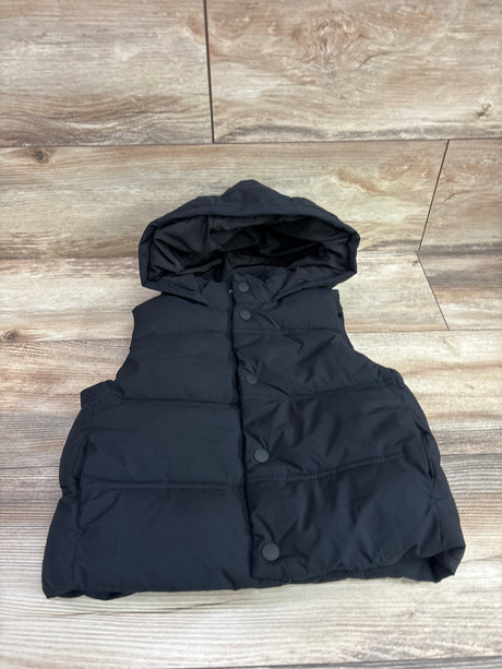 Front view of Zara hooded puffer vest in black, size 2/3T, showcasing its hood and snap-button front on a wood background