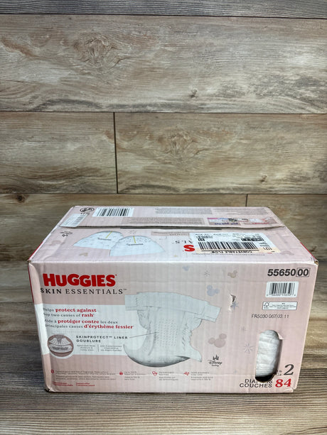 Box of Huggies Skin Essentials size 2 diapers, 84 count, for babies, on wooden background
