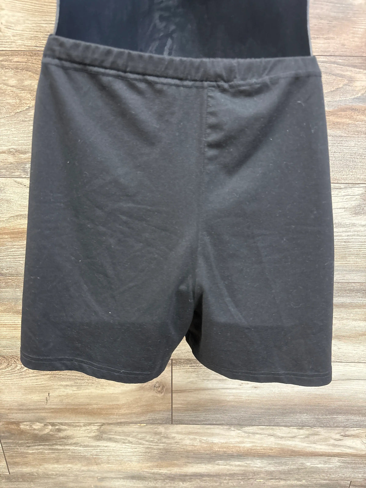 Top view of Ekouaer maternity lounge shorts in black showcasing an elastic waistband on a wood-patterned background
