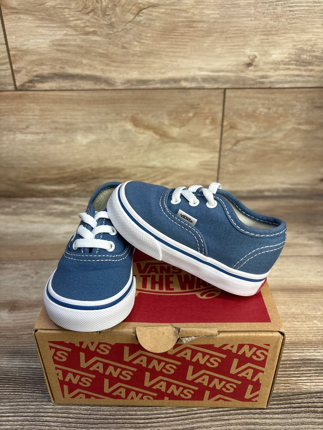 Three-quarter view of navy Vans toddler Authentic sneaker with white laces and rubber sole on Vans box wood background