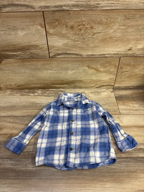 Flat lay of Child of Mine flannel shirt showing blue and white plaid, long sleeves, brown buttons on wood background