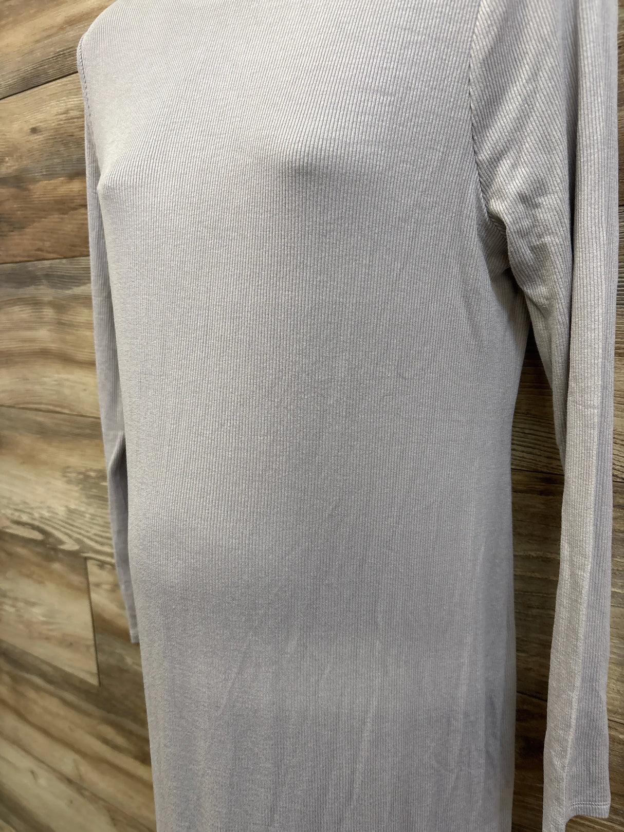 Close-up front of grey ribbed long-sleeve maternity dress on mannequin showing ribbed texture and long sleeves with wood background