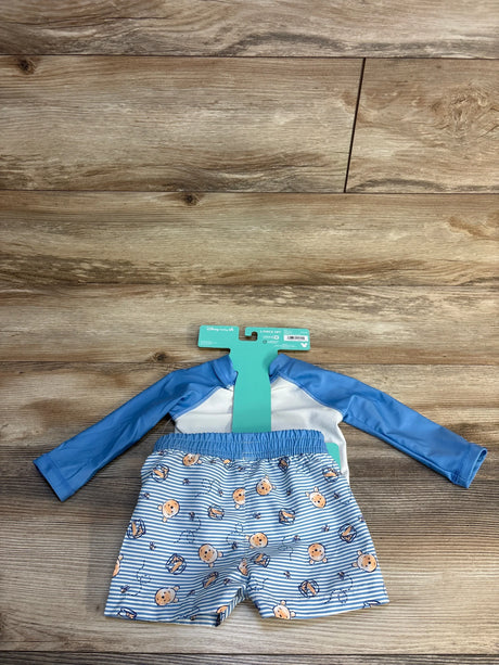 Flat lay of light blue Disney Baby 2-piece Winnie the Pooh rash guard set showing long-sleeve top and striped shorts on wood background