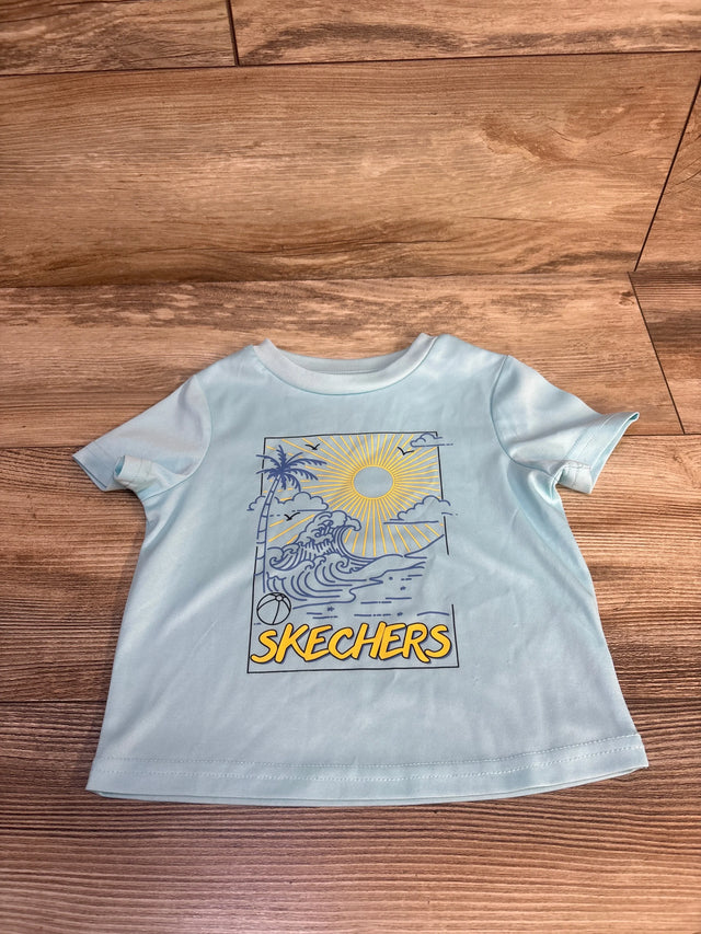 Light blue kids Skechers t-shirt with beach graphic, sun, palm tree, waves, and beach ball on wood floor