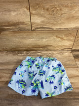 Front view of Cat & Jack swim trunks 4T, light blue with navy and lime tropical print, elastic waistband, on wood background