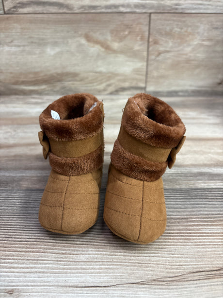 Front view of CRYBOKO brown faux-fur soft-sole boots, size 4/5C, with fur cuffs and side bows on wood