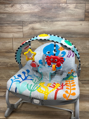 Front view of Baby Einstein Ocean Explorers Opus rocker showcasing ocean-themed seat and toy bar on a wood floor