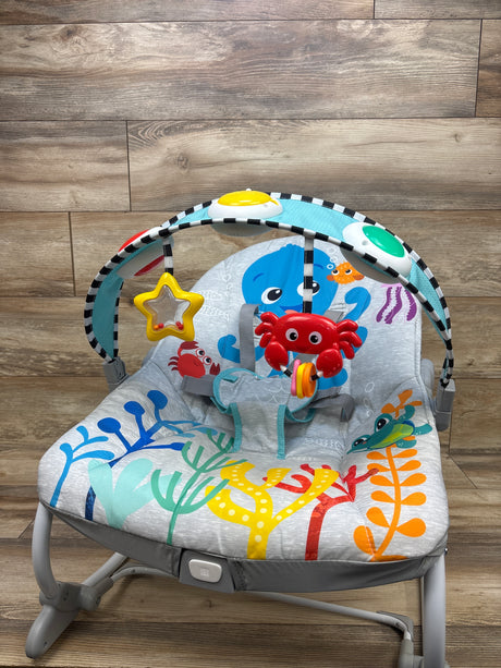 Front view of Baby Einstein Ocean Explorers Opus rocker showcasing ocean-themed seat and toy bar on a wood floor