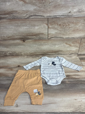 Mickey Mouse baby outfit with striped gray bodysuit and tan pants on wood background