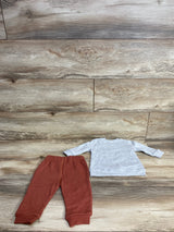 Children's two-piece outfit with rust-colored pants and light gray long-sleeve shirt on wood floor