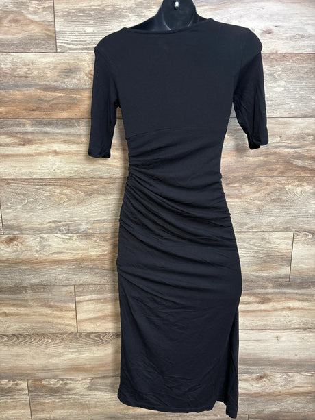 Full-length front view of black maternity short-sleeve dress with side ruching and slit on wood-plank background