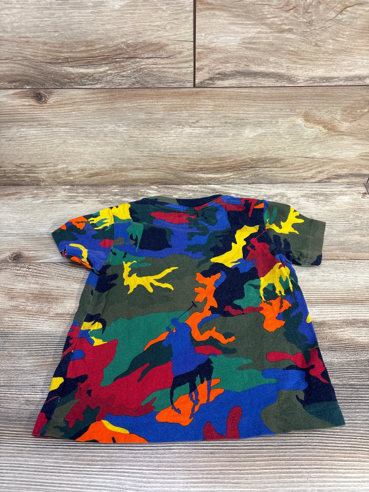 Flat lay back view of Polo Ralph Lauren 3T short sleeve shirt showing multicolored camo and pony motifs on wood floor