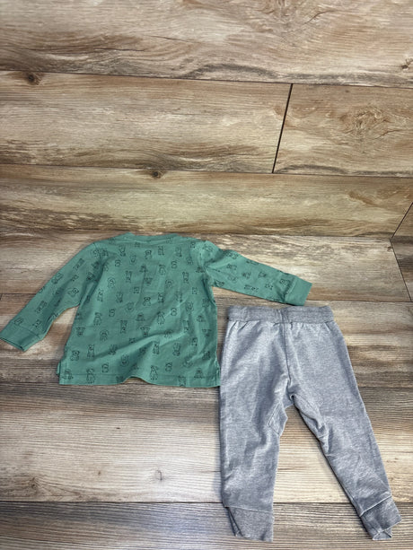 Green long sleeve baby shirt with animal print and gray pants on wood background
