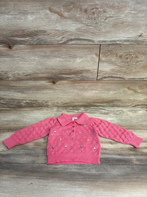 Pink toddler sweater with collar and colorful embroidered patterns, laid flat on wood floor