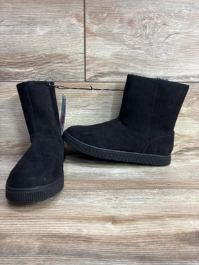 Pair of black suede winter boots with flat rubber soles on wood floor background
