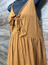 Side close-up of yellow maternity sleeveless dress showing front tie and gathered waist on black mannequin, wood background