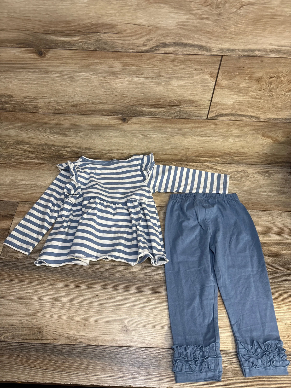 Blue and white striped long sleeve toddler top with blue ruffle leggings on wood background