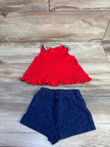 Flat lay of red tank top and navy eyelet shorts set showcasing ruffled hem and eyelet embroidery on wood background