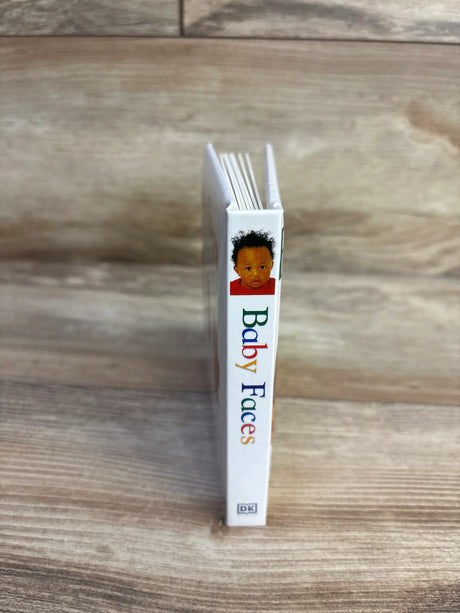 Spine view of Baby Faces DK board book showing colorful title text and infant cover photo standing on wood plank floor
